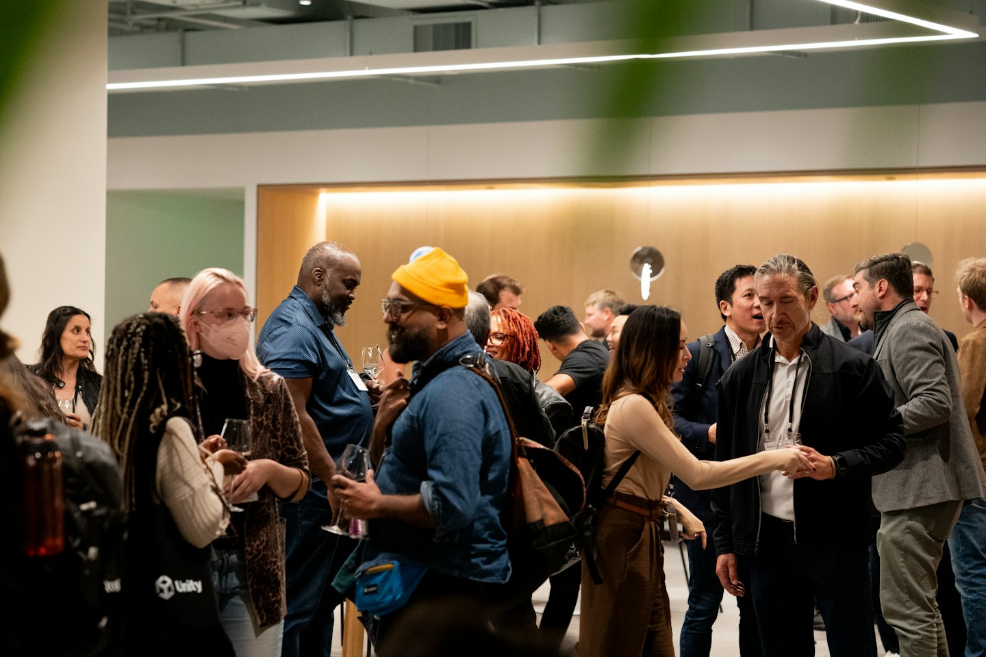 Professionals die netwerken en wijnglazen vasthouden tijdens een evenement binnen.